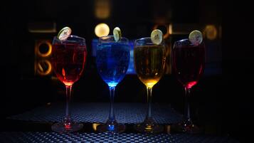 Four glasses of different colored beverages on a table with a checkered pattern.