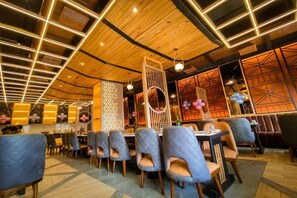 A restaurant with a modern interior, featuring wooden ceiling panels and geometric wall designs. - Hotel Park Regency (Gorakhpur)