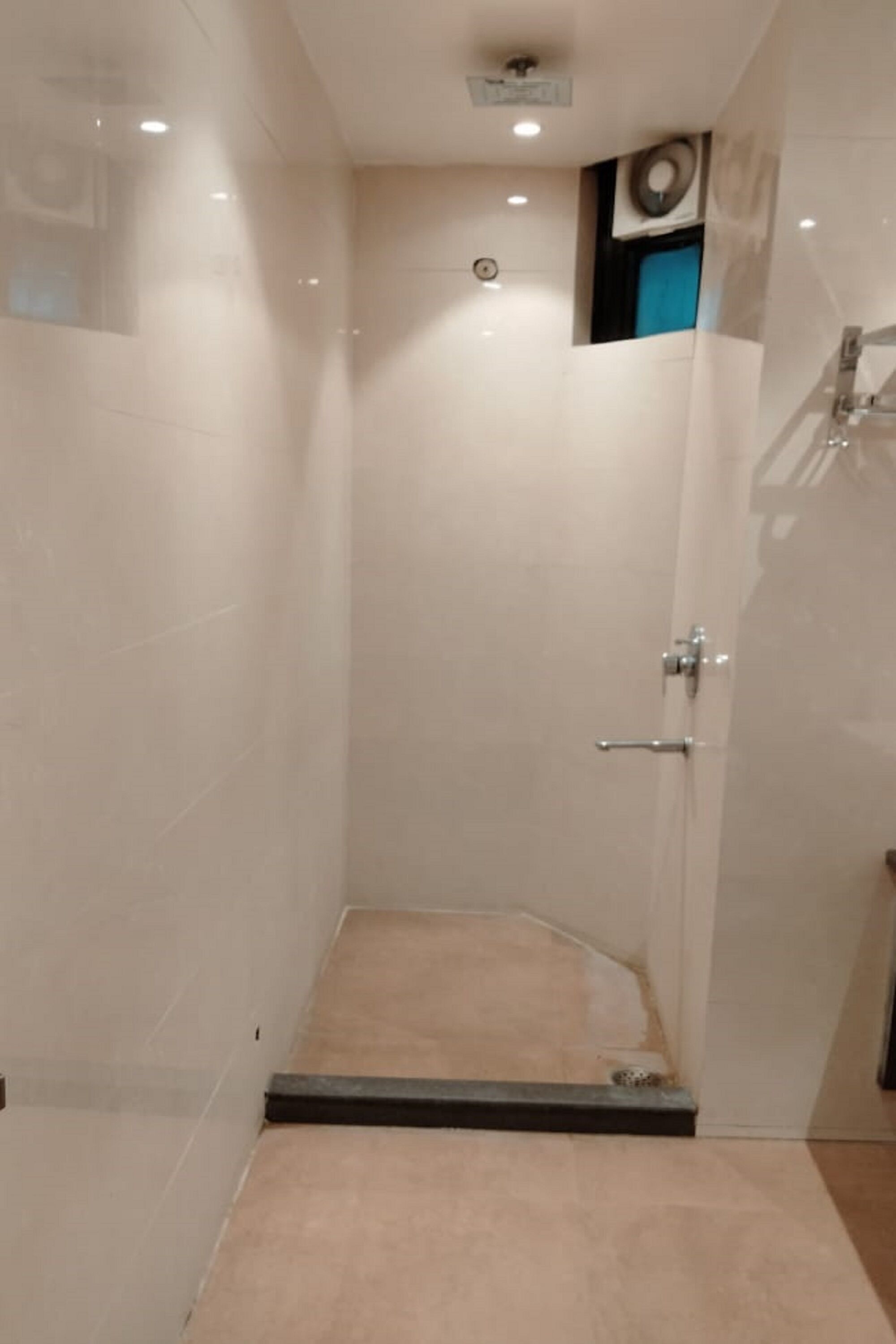A modern shower with a glass door, a visible control panel, and a small window.