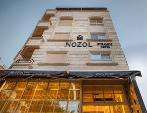 The exterior of the Nozol Pyramids Hotel with a clear view of the building's facade, including the name and logo.