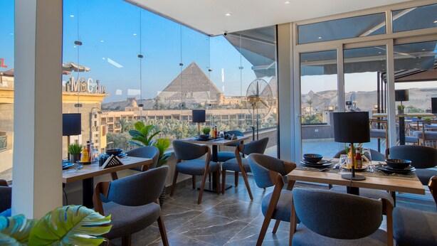 Comedor con vista a la pirámide, sillas modernas y una mesa con lámpara.
