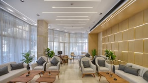 Un moderno vestíbulo de hotel con sofás, sillones, una mesa de centro y una zona de trabajo.