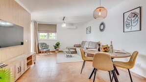 Uma sala de estar moderna com televisão, sofá, mesa de jantar e cadeiras.