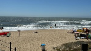 Une plage où des gens se prélassent au soleil et où un drapeau est planté dans le sable.