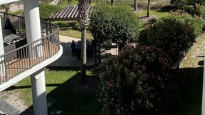 Un balcon extérieur à plusieurs niveaux offrant une vue sur une plage et l’océan.