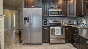 Une cuisine moderne avec des meubles en bois foncé, des appareils électroménagers en acier inoxydable et un dosseret carrelé.