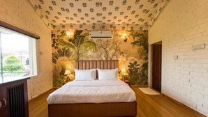 A bedroom with a large bed, a window, and a wall with a plant mural. - Vanbagh Sariska Resort (Alwar)