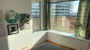 A bedroom with a bed, a window with curtains, and motivational wall art.