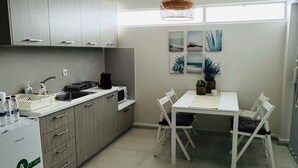 Une cuisine moderne avec des meubles gris, un plan de travail blanc, une table à manger avec des chaises et un ventilateur de plafond.