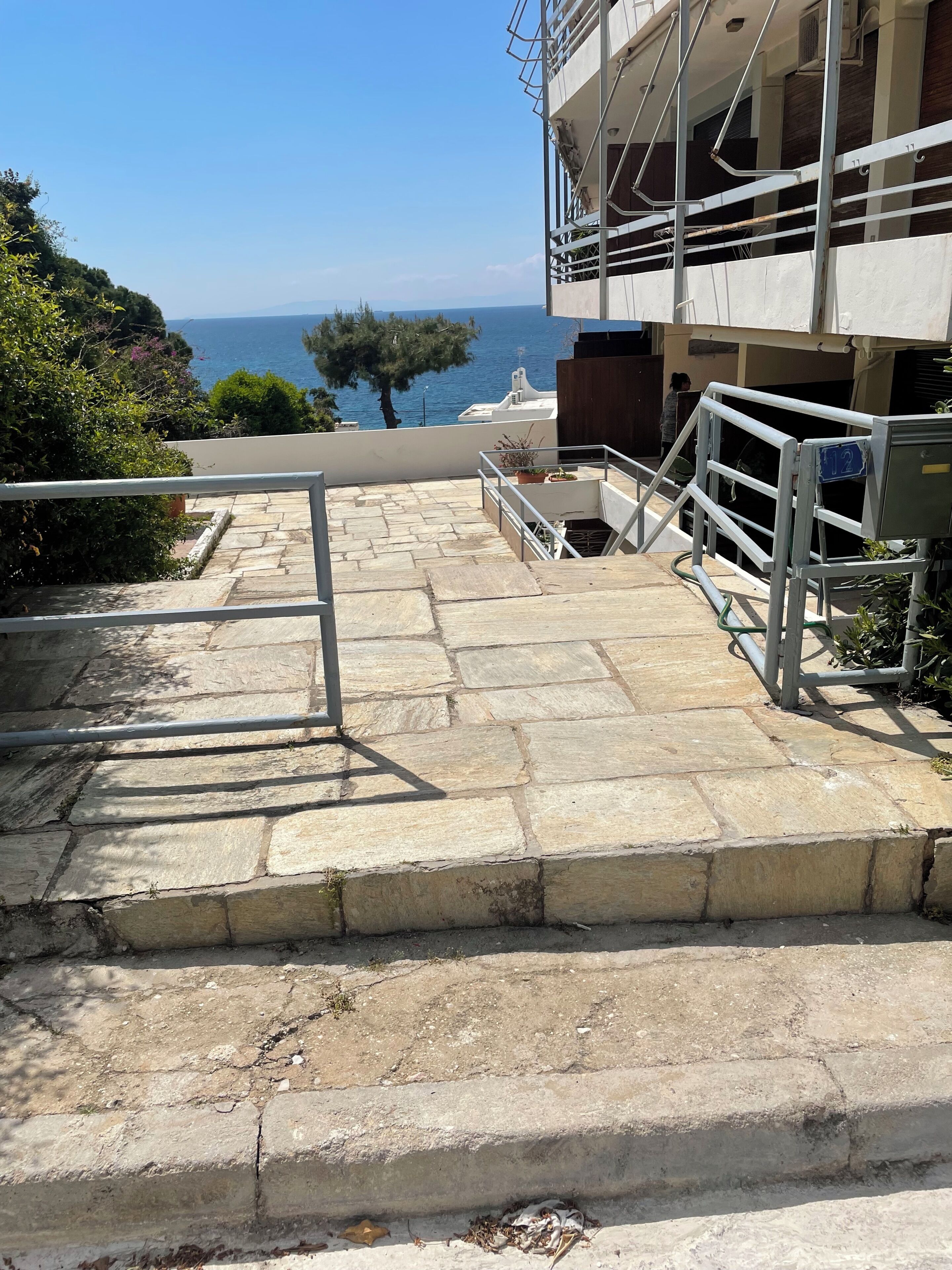 A stone staircase leading to a building with a view of the sea.