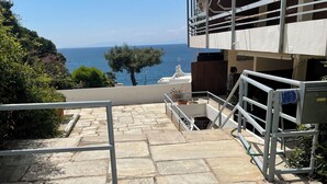 Un escalier en pierre menant à un bâtiment d’où l’on a vue sur la mer.