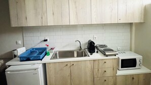 Una cucina con mobili in legno, un piano di lavoro bianco, un lavello, un forno a microonde e un frigorifero.
