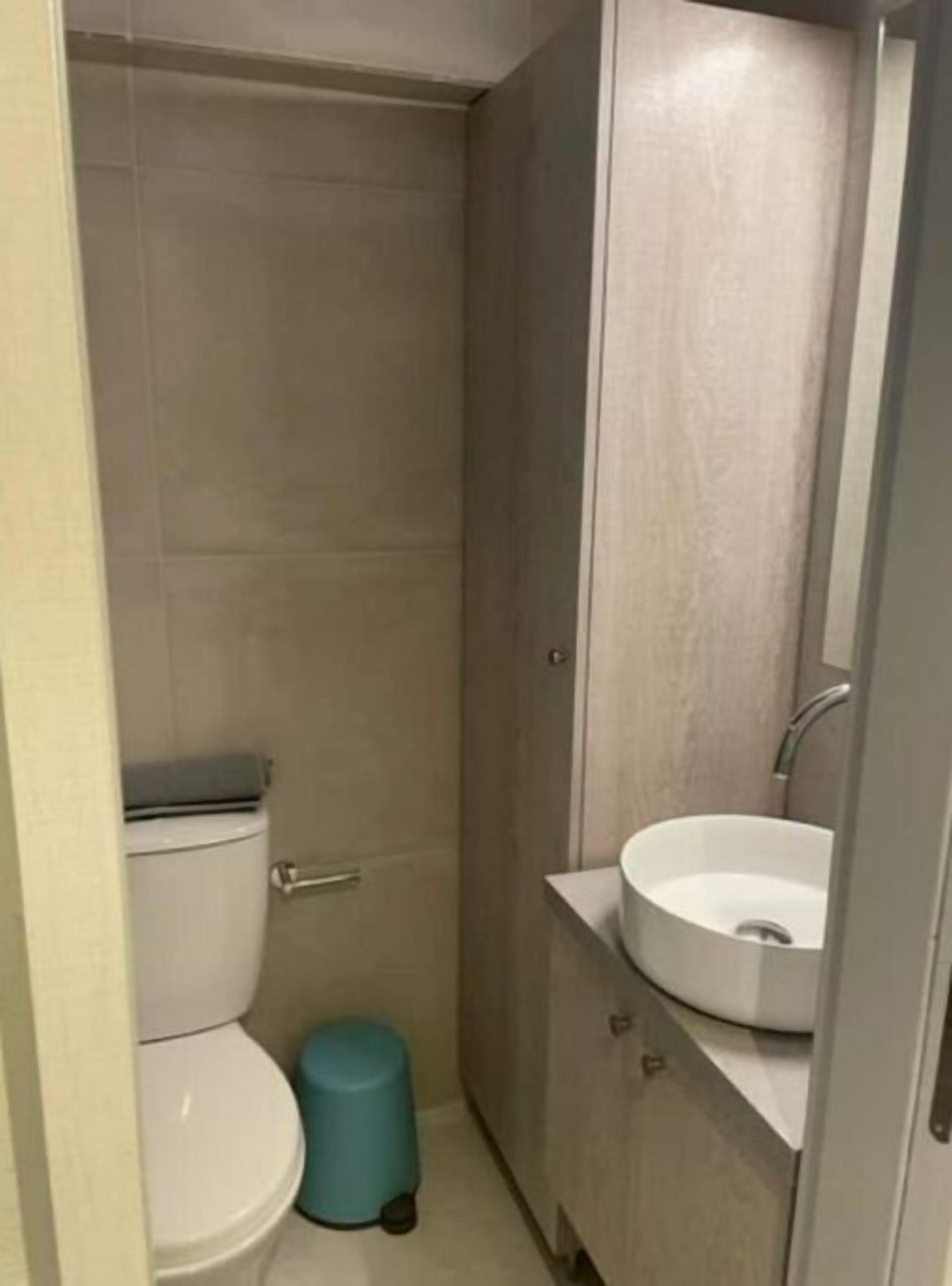 Pieni, moderni kylpyhuone, jossa on wc, pesuallas ja roskakori.