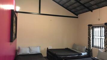 A room with two beds, a chair, and a window with curtains.