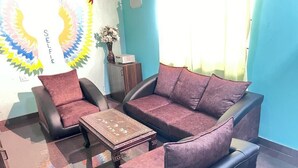 Une pièce avec un mur bleu, un canapé, une chaise et une petite table.