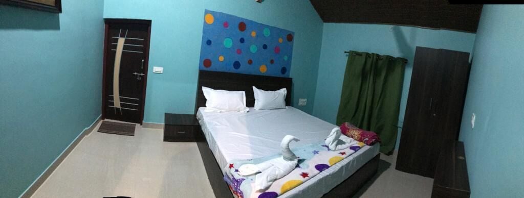 A bedroom with a bed, a door, a wall with a polka dot pattern, and a green curtain.