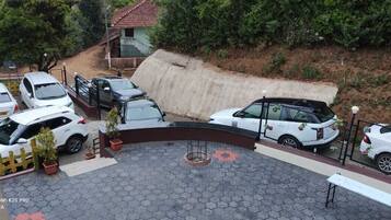 Un área de estacionamiento con varios coches blancos, una barrera de hormigón y un pequeño edificio con techo rojo.