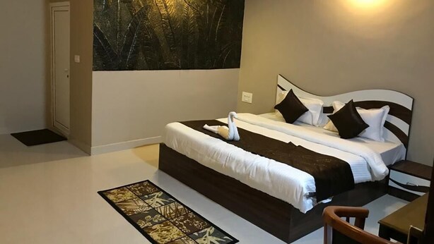 Une chambre à coucher avec un grand lit, une table de chevet, une chaise et une œuvre d’art accrochée au mur.