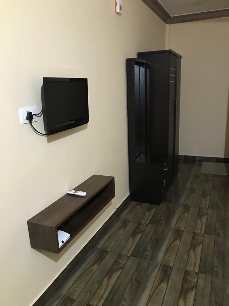 A room with a mounted TV, a built-in shelf, and a wardrobe.