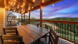 Une terrasse en bois avec une table et des chaises, offrant une vue sur un paysage magnifique.