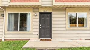 A two-story building with a dark front door, beige siding, and a small porch.