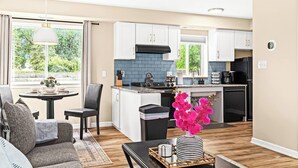 A modern kitchen with white cabinets, a blue backsplash, and a black refrigerator.