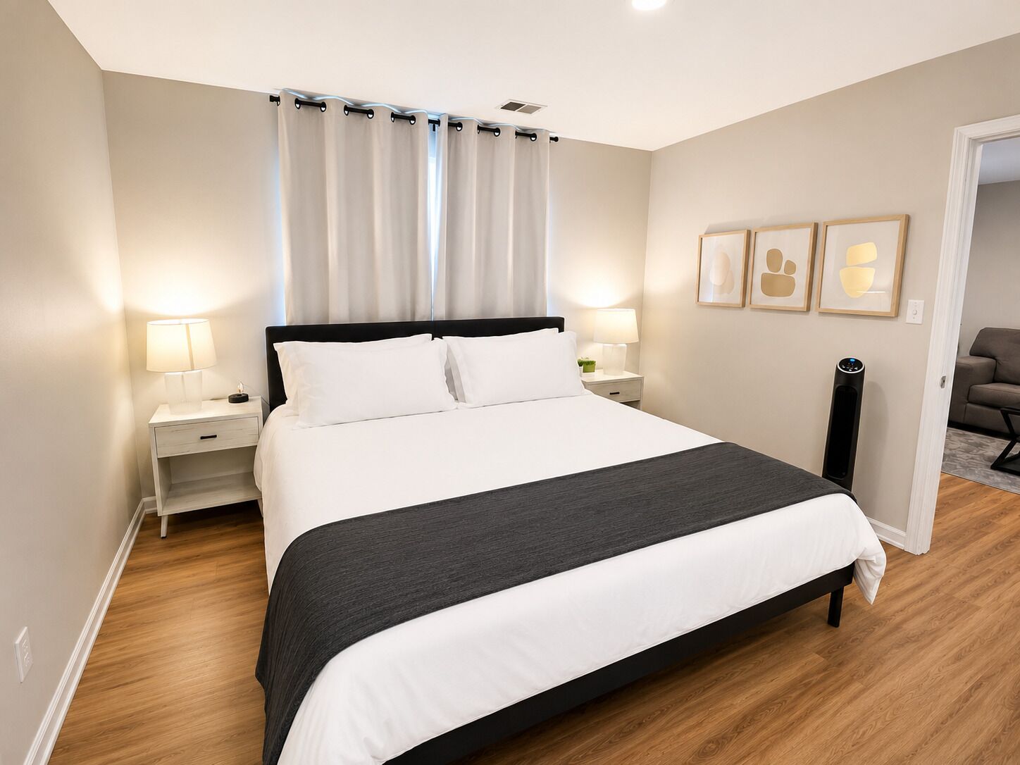 A modern bedroom with a large bed, bedside lamps, a nightstand, and a wall-mounted radiator.