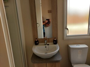 A bathroom with a white sink, wooden vanity, and a toilet.