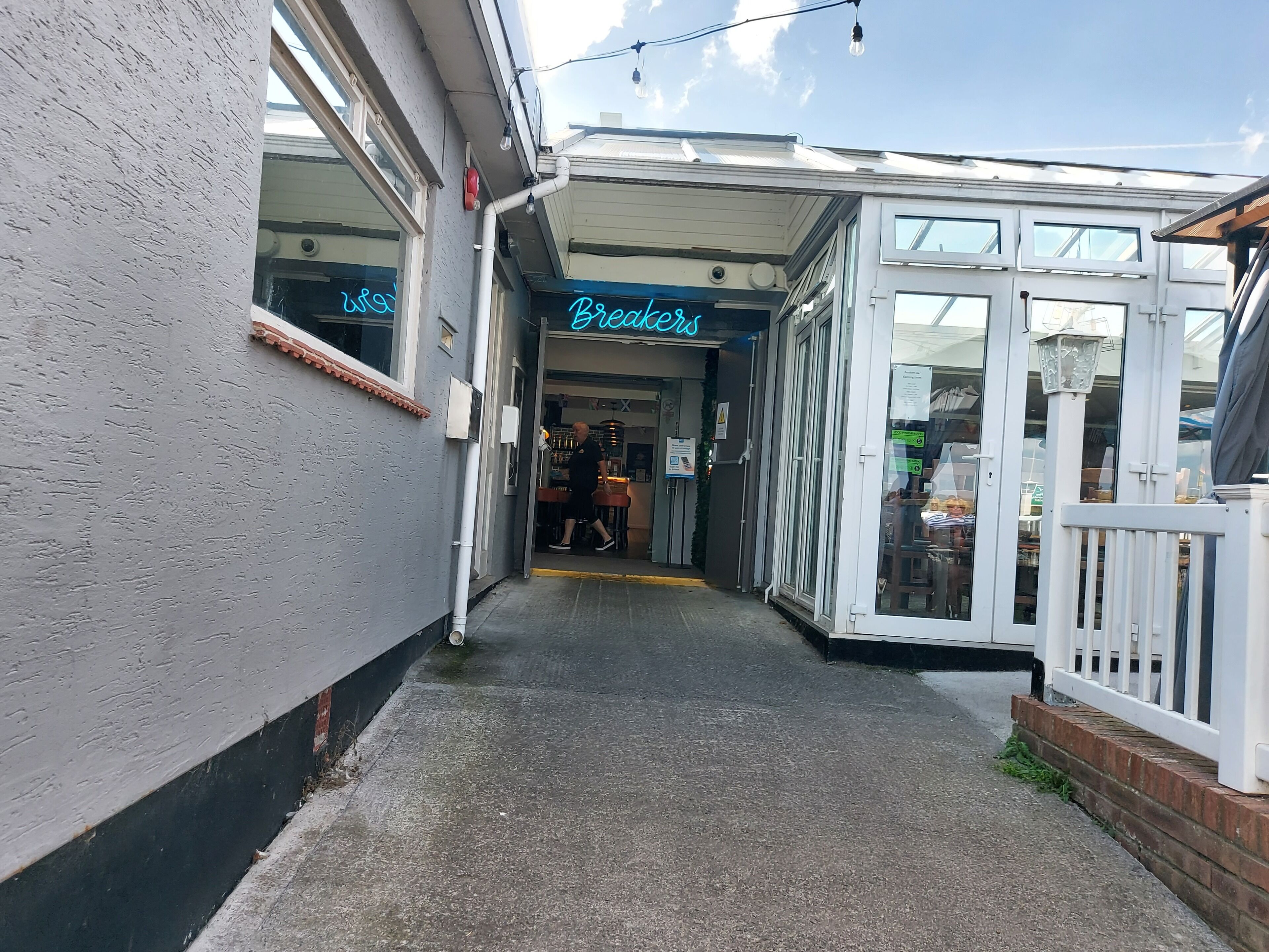 A narrow alleyway leading to a building with a neon sign reading "Brexners."
