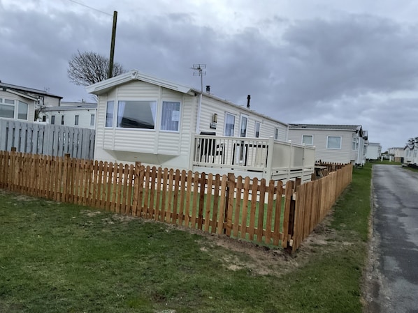 A row of mobile homes with a wooden fence in front.