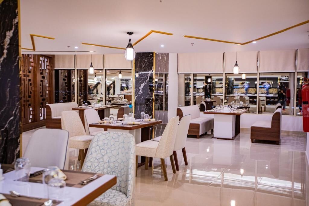 A modern restaurant with multiple dining areas, including a bar and a seating area with a view of the kitchen.