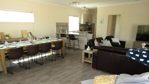 Una sala de estar moderna con un sofá, una mesa de comedor para cuatro personas y una zona de cocina al fondo.