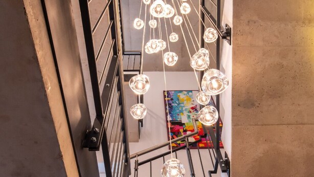 Modernilla designilla varustetut portaat, joissa on metallikaide ja riippuvat valaisimet.