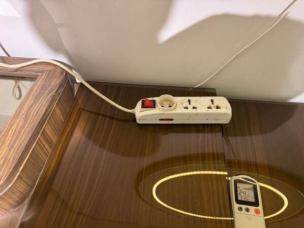 A power strip with a digital thermometer on a wooden surface.