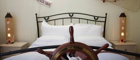 Un lit avec une tête de lit en forme de barre de navire, deux tables de chevet et un panneau indiquant « Bar de plage ».