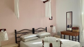 A bedroom with a bed, bedside tables, a nightstand, a mirror, and a window with curtains. - B&B La cascata (Noci)