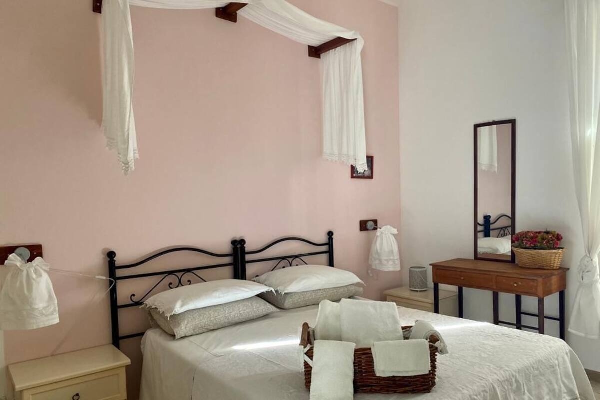 Ein Schlafzimmer mit einem Bett, Nachttischen, einem Schminktisch, einem Spiegel und einem Fenster mit Vorhängen.