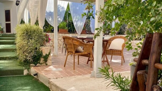 A covered outdoor seating area with wicker chairs and a stone pathway. - B&B La cascata (Noci)
