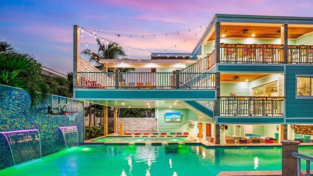 A multi-story building with a swimming pool, outdoor seating, and a balcony with string lights.