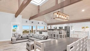 A spacious kitchen with a large island, white cabinetry, and a modern pendant light.