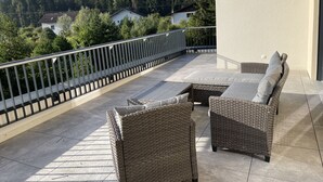 Un balcone con mobili in vimini e vista sulle montagne.