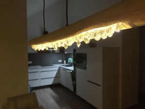 Une cuisine moderne avec des armoires blanches, un plan de travail en bois et un luminaire suspendu.