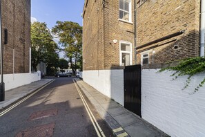 A narrow street with brick buildings, a white wall, and a black gate. - The Westbourne Villa (London)