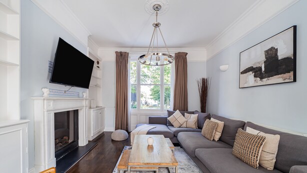 A living room with a fireplace, a television, a sofa, and a coffee table. - The Westbourne Villa (London)