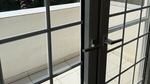 A view through a window with a grid pattern, a door handle, and a tiled floor. - Miklat for 6/7, Family Villa By The Sea W Jacuzzi & Pool (Caesarea)