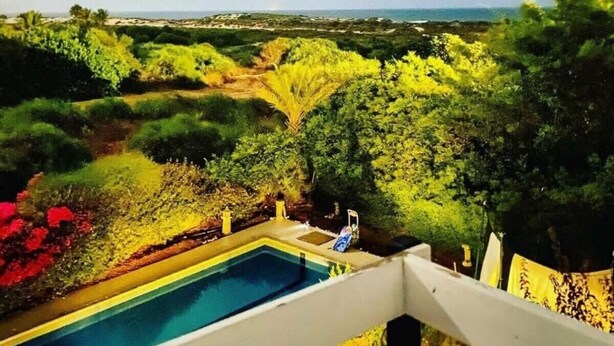 A pool with a view of a beach and dense greenery. - Miklat for 6/7, Family Villa By The Sea W Jacuzzi & Pool (Caesarea)