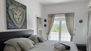 A bedroom with a large bed, a painting of a lion, and a view through a window. - Miklat for 6/7, Family Villa By The Sea W Jacuzzi & Pool (Caesarea)