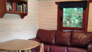 Una habitación acogedora con una estantería de madera, un sofá de cuero rojo, una mesa de madera y una alfombra estampada.