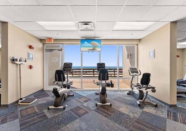 Gimnasio con equipo de ejercicio, vista a la playa y señal de salida.