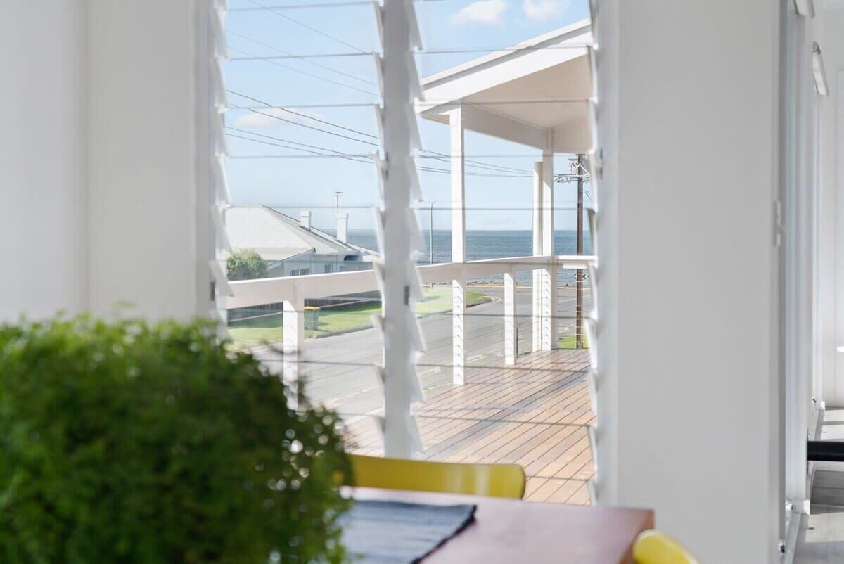 A balcony with a view of the sea and a building in the background.